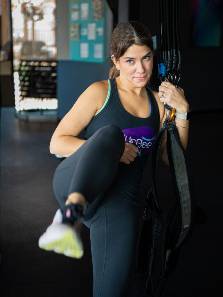 Woman doing a knee drive while holding a bungee strap