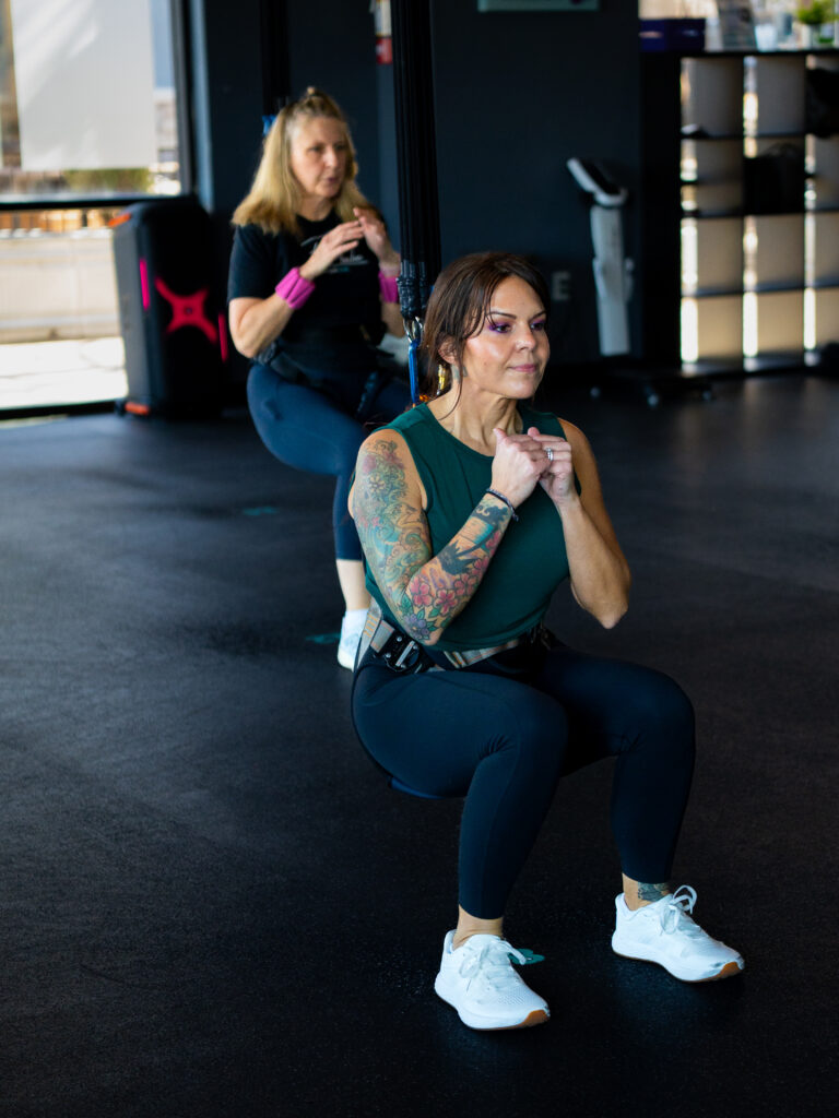 Woman in a bungee harness squatting with fists raised
